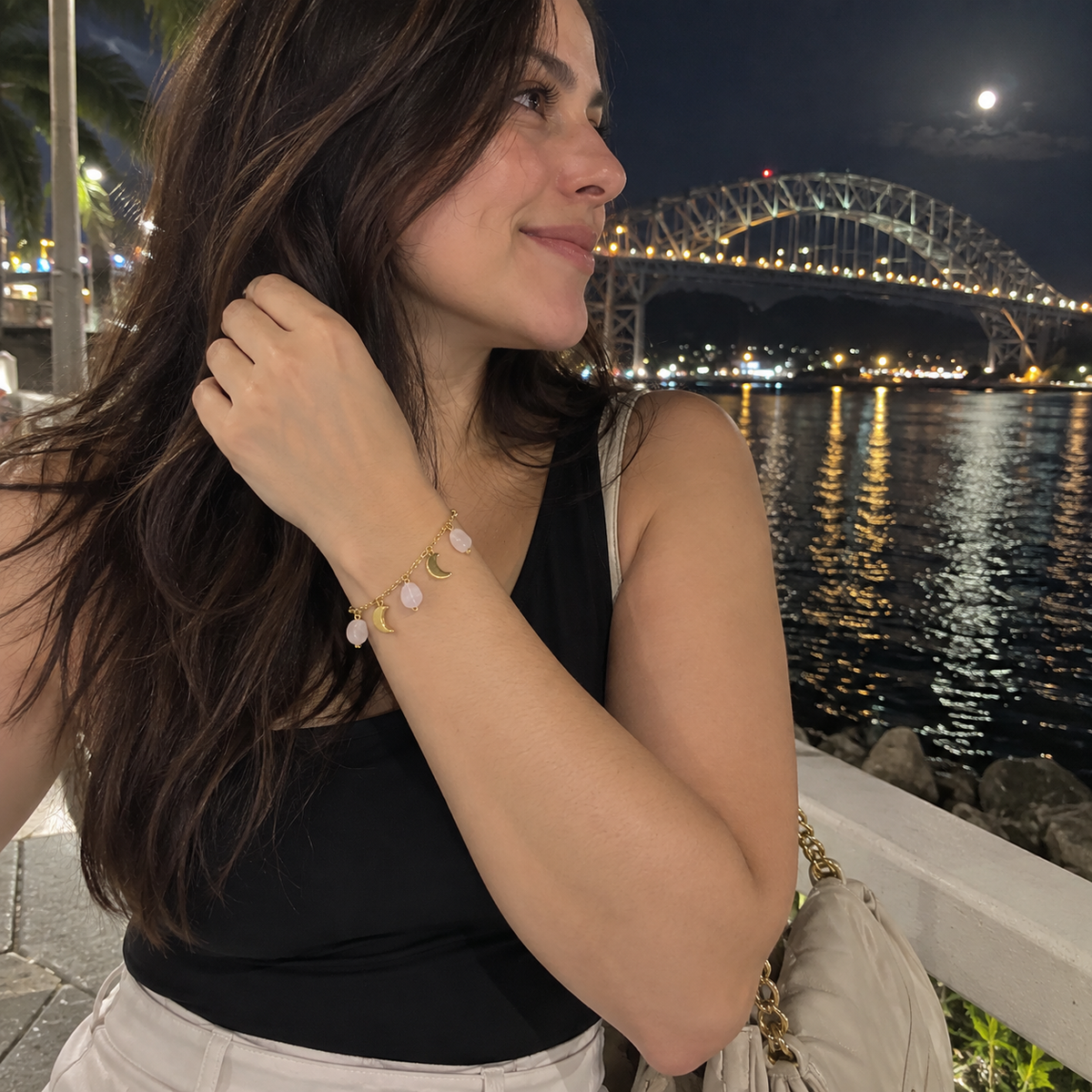 Mujer usando la Pulsera Amor de cuarzo rosado durante un paseo por el puente de las americas