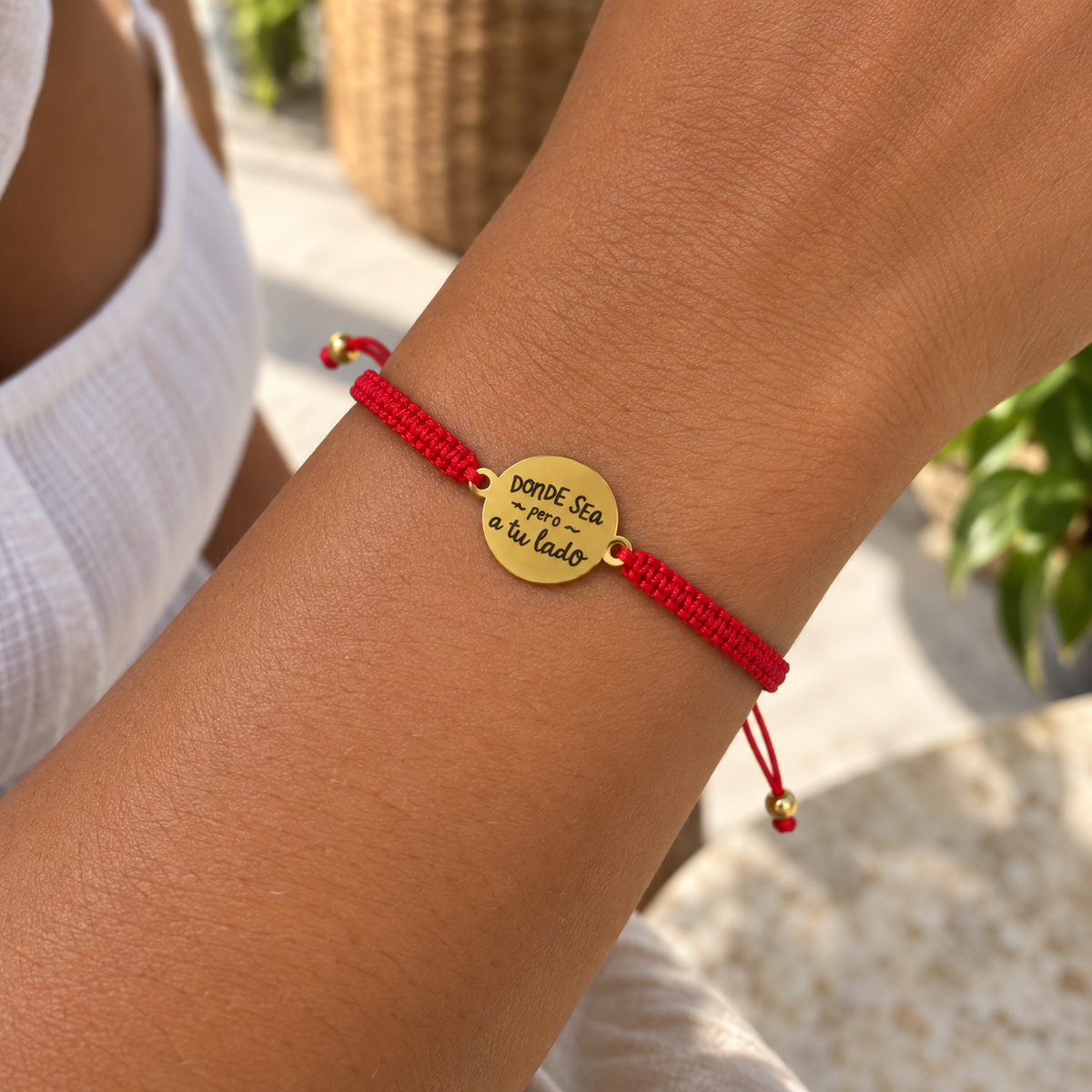 Detalle de pulsera de hilo rojo con dije de acero inoxidable