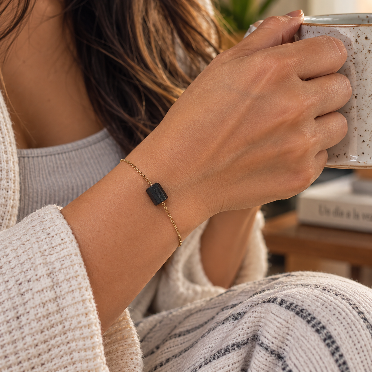 Mujer usando la Pulsera de turmalina negra mientras disfruta de una bebida